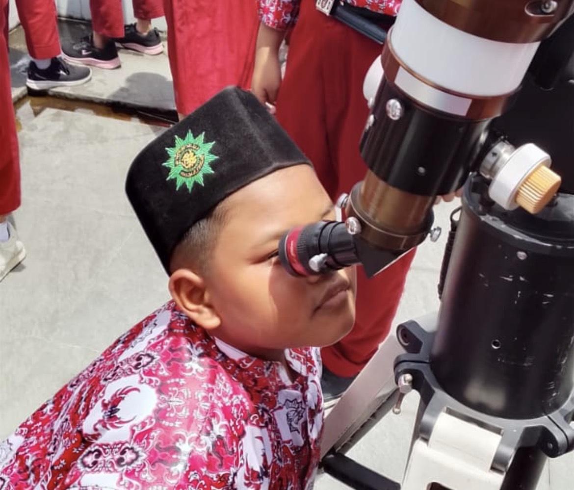 Siswa SD Muhammadiyah 12 Semarang memakai peci berlogo Muhammadiyah sedang mengamati benda langit menggunakan teleskop saat Outing Class Pendidikan Karakter.