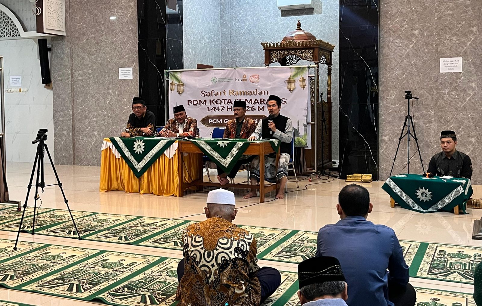 Empat pimpinan Muhammadiyah duduk di meja depan yang dilapisi taplak hijau motif matahari, berada di depan spanduk acara Safari Ramadhan di sebuah masjid dengan dinding marmer abu-abu.