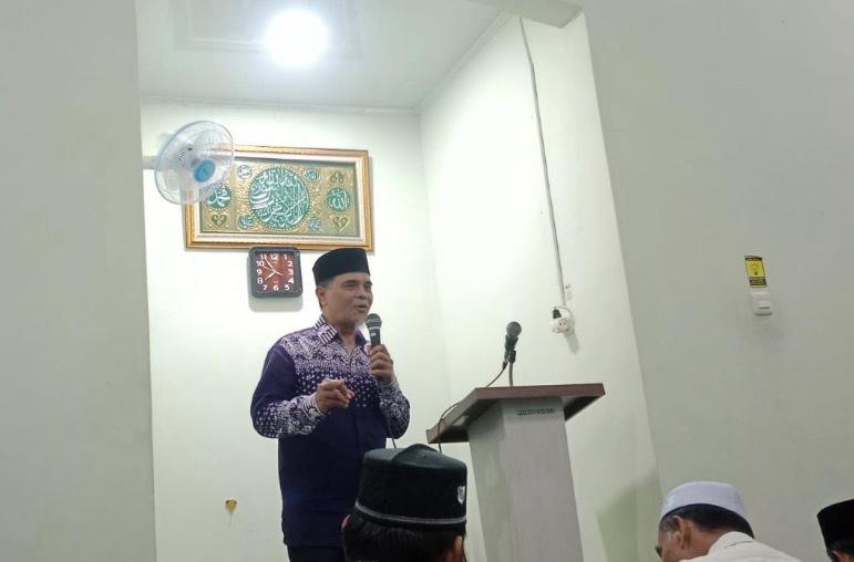 Ustadz Amin mengenakan batik biru dan peci hitam sedang memberikan tausiyah amalan malam Ramadan di atas podium Masjid Asy Syifa Semarang.