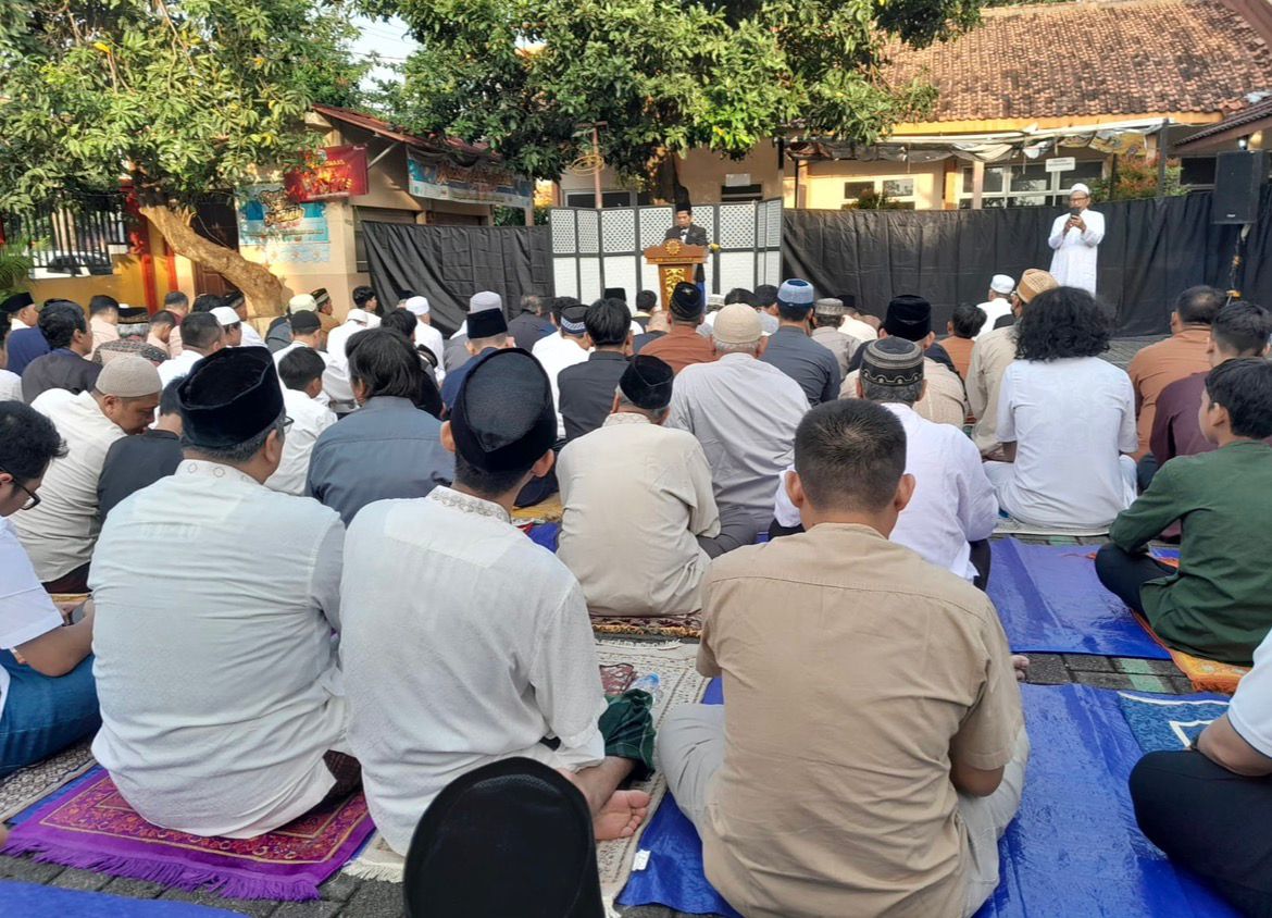 Jamaah pria duduk di atas sajadah mengikuti Sholat Idul Fitri di halaman SD Sampangan 02 Gajahmungkur Semarang, mendengarkan khotbah dari Ustadz Danusiri di mimbar.