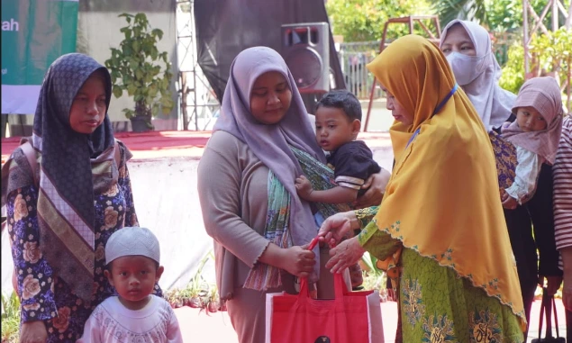 Seorang kader Aisyiyah Jateng berkerudung kuning menyerahkan bantuan paket gizi kepada ibu balita sebagai ilustrasi langkah nyata intervensi keluarga dalam pencegahan stunting jateng.