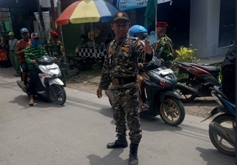 Anggota Banser NU berseragam loreng sedang mengatur lalu lintas bersama personel Kokam Muhammadiyah berbaret merah dalam perhelatan Hari Ber-Muhammadiyah di jalan raya Genuk, Kota Semarang.