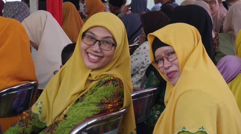 Dua orang kader Aisyiyah mengenakan jilbab kuning dan seragam batik tersenyum di tengah jamaah Hari Bermuhammadiyah Semarang.