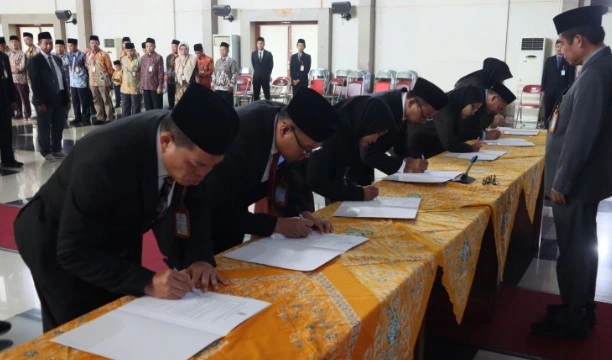 Deretan pimpinan baru, termasuk para tokoh Muhammadiyah, sedang membungkuk untuk menandatangani berita acara sumpah jabatan di atas meja berbalut kain kuning dalam prosesi pelantikan pejabat UIN Walisongo.