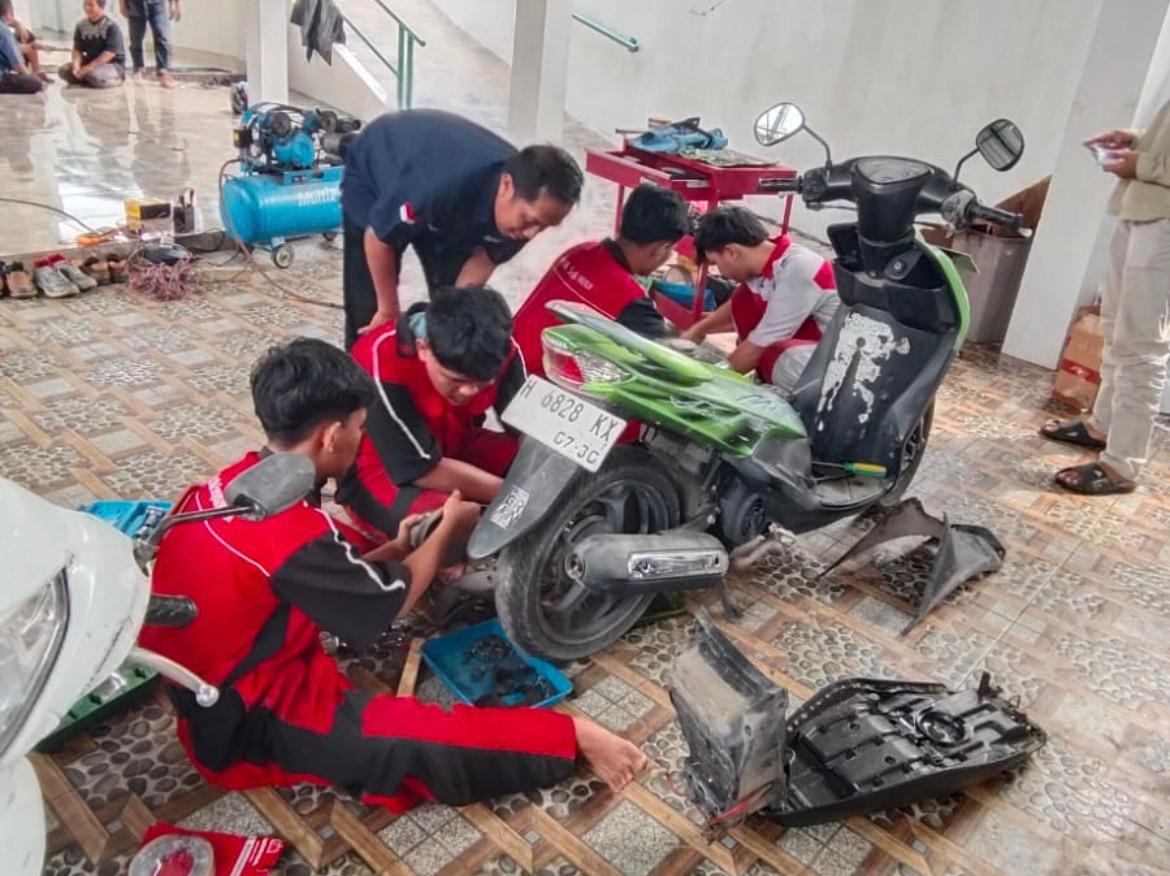 Siswa SMK Muhammadiyah 2 Kota Semarang sedang memperbaiki mesin sepeda motor warga yang rusak akibat terendam lumpur banjir Ngaliyan Semarang di posko darurat Kelurahan Purwoyoso.