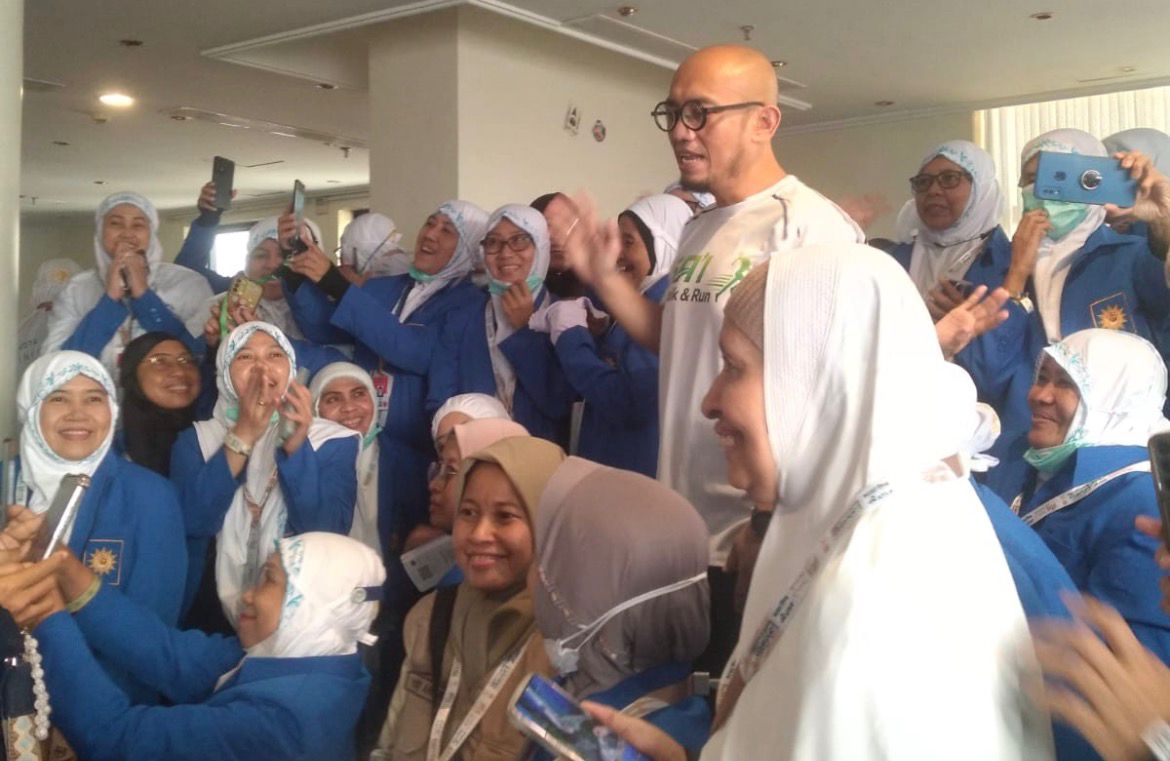 Suasana antusias jemaah haji wanita Kloter SOC 28 mengenakan seragam biru dan jilbab putih mengerumuni Wakil Menteri Haji Dahnil Anzar Simanjuntak untuk berswafoto (selfie) menggunakan smartphone di lobi hotel Makkah.