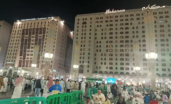 Suasana Subuh jemaah haji beraktivitas di pelataran Masjid Nabawi dengan latar belakang gedung Makareem Haram View Suites dan Taiba Front, yang merupakan fasilitas hotel jemaah haji Madinah 2026 untuk Kloter 28 SOC Semarang