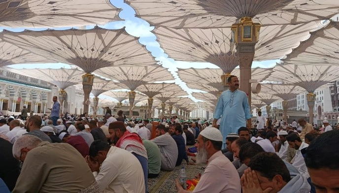 Lautan jemaah haji duduk bersaf di pelataran luar di bawah naungan payung raksasa saat pelaksanaan Jumatan Masjid Nabawi akibat area dalam masjid penuh.