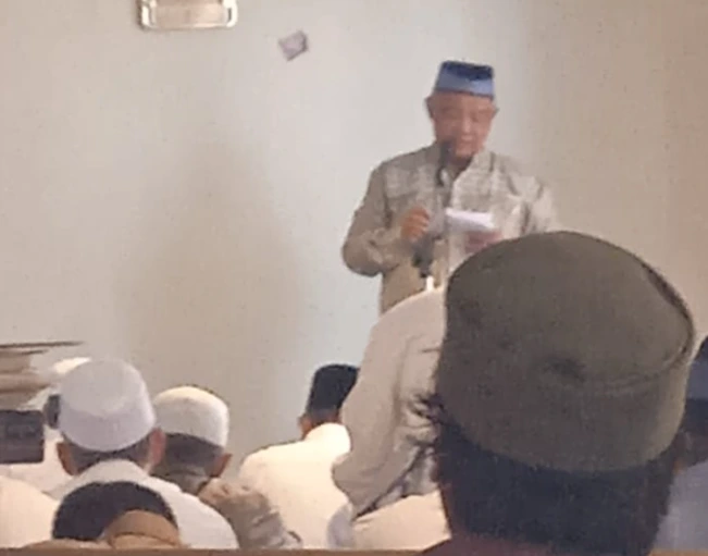 Dr. Mafrukhi, Ketua Kafilah Muhammadiyah Kloter 28 SOC Semarang, menyampaikan khutbah Jumat pertama di Makkah (15 Mei 2026) di ruang shalat Hotel Rose Almashair Raudhah, di depan jemaah haji yang duduk mendengarkan dari belakang. Dia terlihat memegang catatan di kertas.