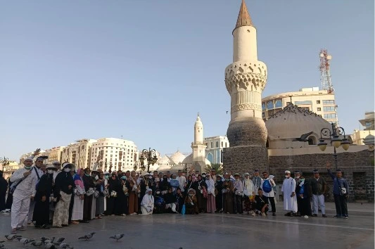 Rombongan jemaah haji Semarang Kloter 28 SOC Muhammadiyah berfoto bersama berlatar menara kuno Masjid Ghamamah di Madinah dalam rangkaian perjalanan menuju ziarah Makam Baqi.