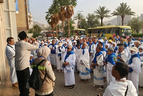 Ustadz Nurbini memberikan pengarahan persiapan umrah wajib perdana kepada rombongan jemaah haji Kloter 28 SOC berseragam ihram di halaman hotel, wujud pantauan kondisi jemaah haji Makkah terkini.