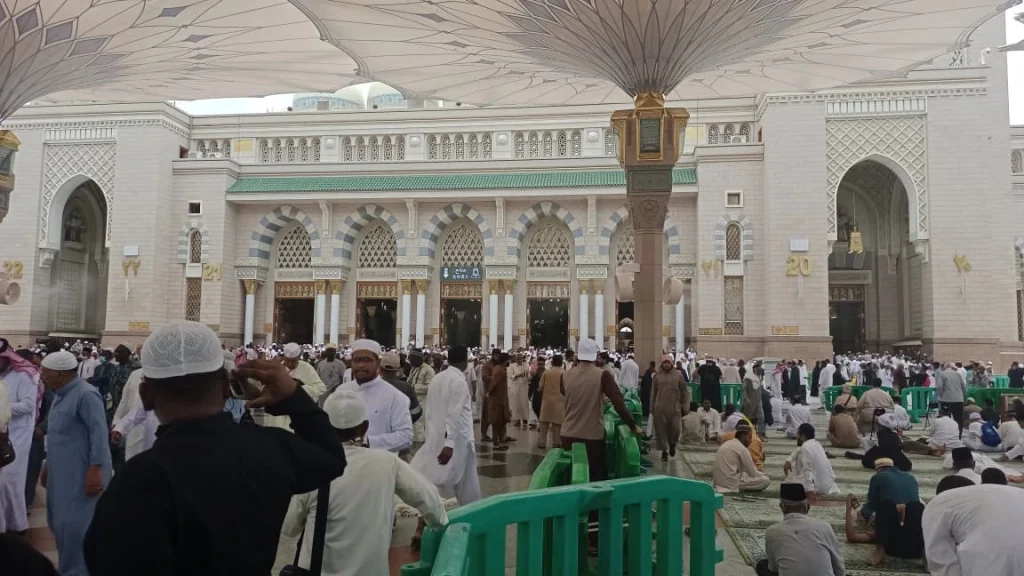 Suasana pelataran Masjid Nabawi di bawah naungan payung raksasa dengan ribuan jemaah haji yang diatur oleh barikade hijau.