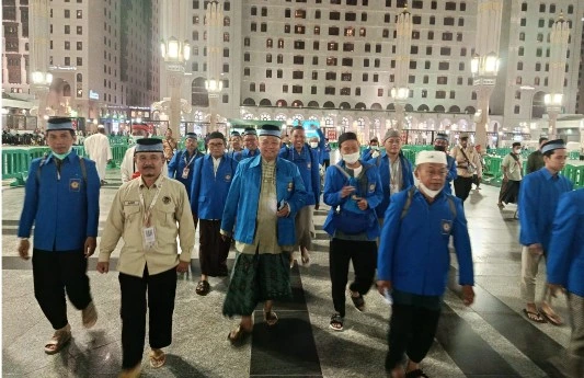 Ustadz Nurbini yang mengenakan baju krem memimpin rombongan jemaah haji laki-laki Kloter 28 SOC Semarang berseragam biru berjalan meninggalkan pelataran usai salat tahajud di rooftop Masjid Nabawi menuju Makam Baqi.
