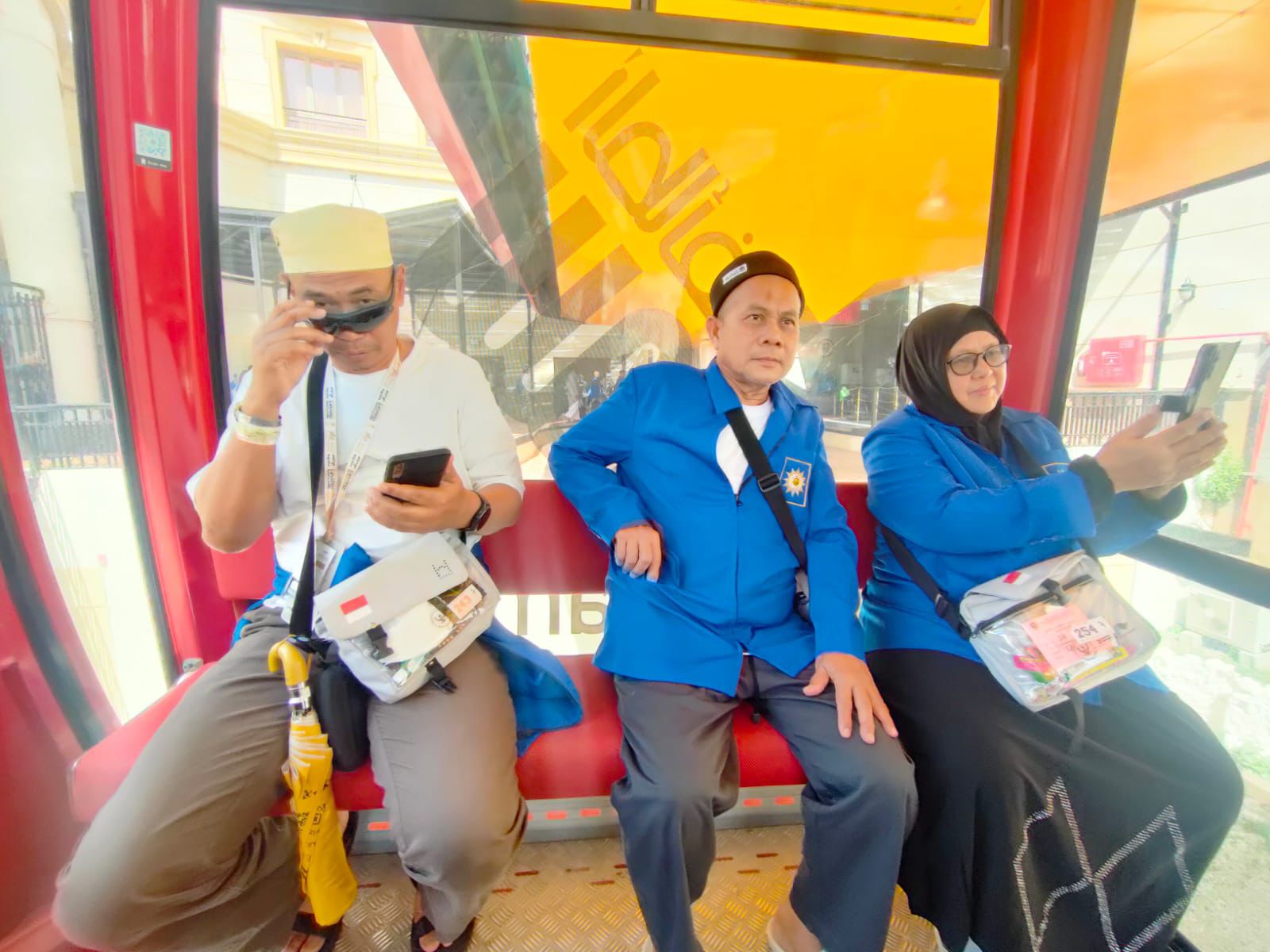 Tiga jemaah haji Indonesia KBIHU Muhammadiyah Kota Semarang mengenakan seragam biru sedang duduk di dalam kereta gantung atau gondola saat mengikuti tur wisata religi di Kota Taif, Arab Saudi.