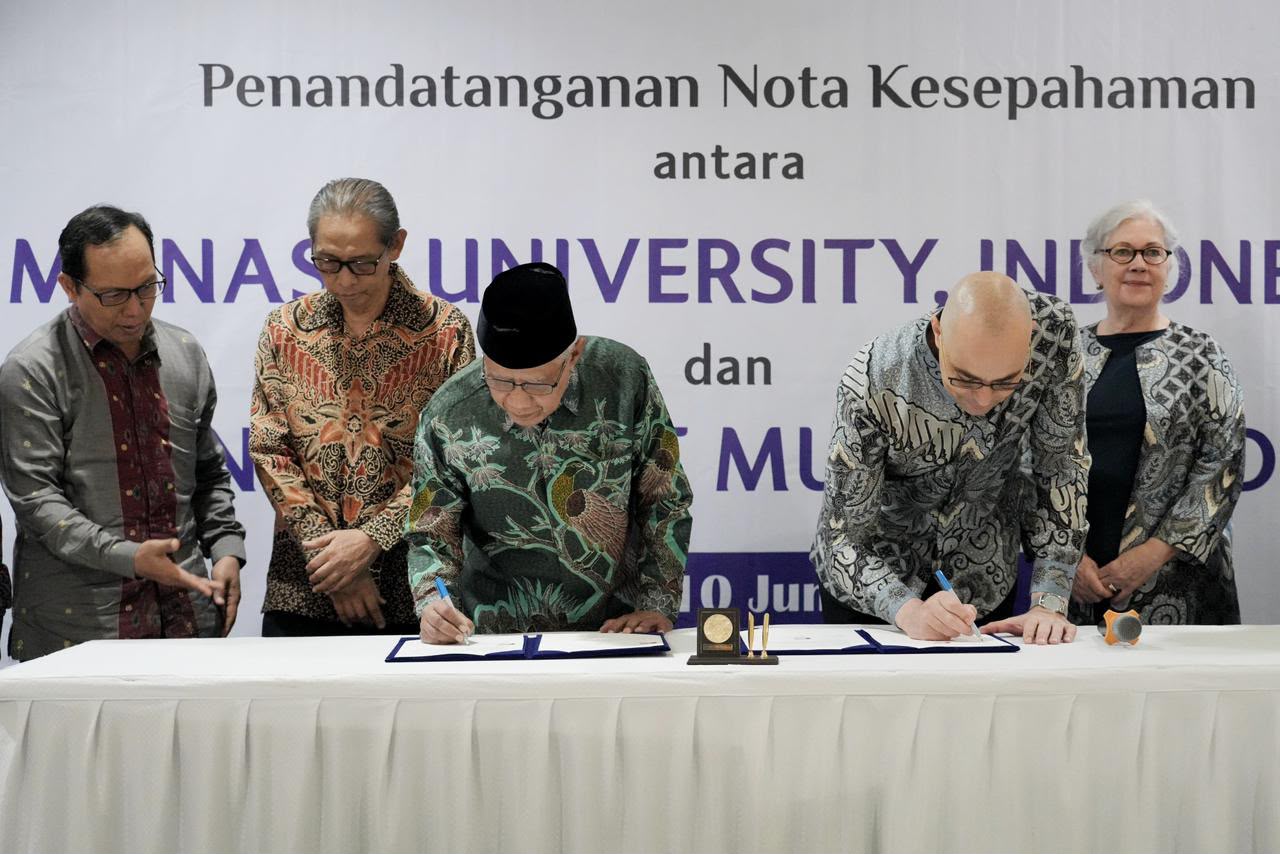 Lima orang pejabat berfoto saat penandatanganan nota kesepahaman antara Monash University, Indonesia dan PP Muhammadiyah. Haedar Nashir yang mengenakan peci hitam menandatangani dokumen di tengah.