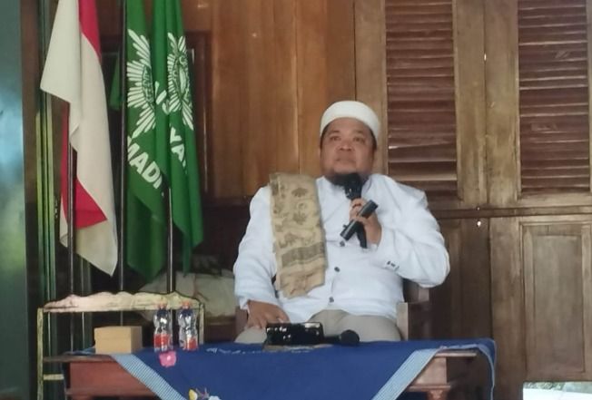 Ust HM Budi Hidayat sedang memegang mikrofon saat menyampaikan kajian tentang makna hijrah di era modern dan cara mengatasi overthinking menurut Islam.