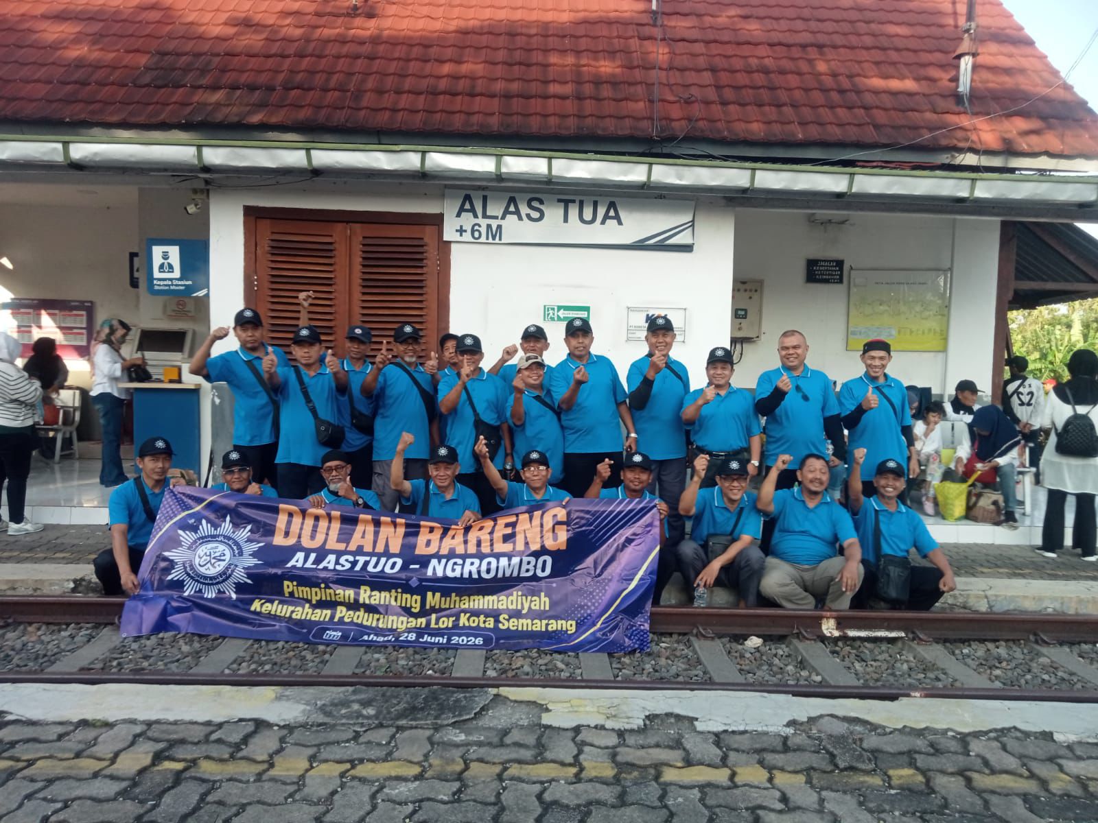 Sekelompok jemaah pria berseragam biru dari komunitas Masjid At-Taqwa Pedurungan berfoto memegang spanduk "Dolan Bareng" di depan papan nama Stasiun Alastua Semarang sebagai wujud inovasi dakwah kultural milenial.