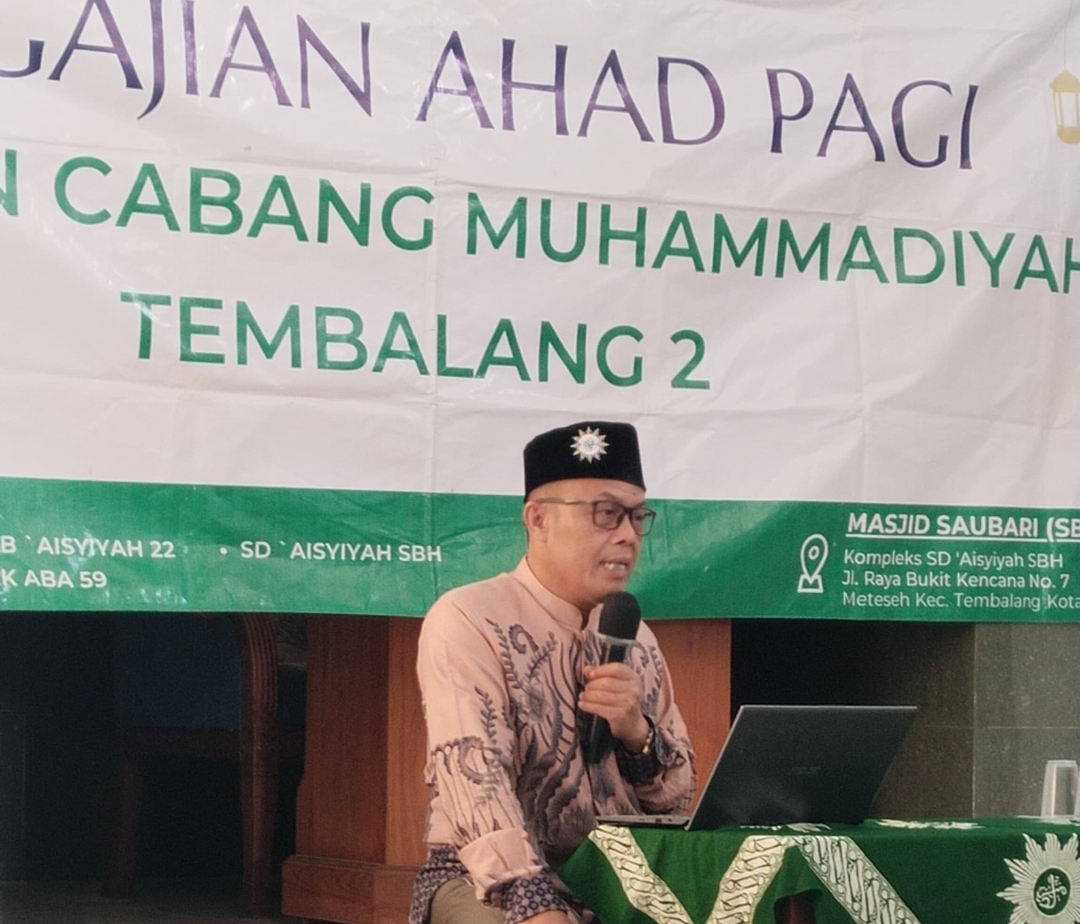 Sekretaris PDM Kota Semarang H. Suparno BM sedang memberikan ceramah mengenai tips keluarga sakinah menggunakan mikrofon dan laptop di depan spanduk Pengajian Ahad Pagi Cabang Muhammadiyah Tembalang 2.
