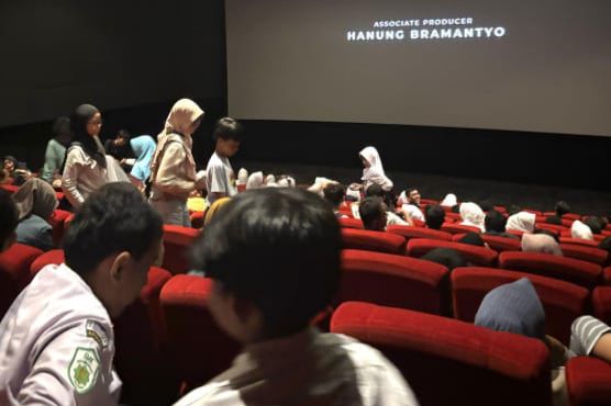 Suasana di dalam studio bioskop yang dipenuhi oleh para siswa-siswi SMK Muhammadiyah 1 Semarang berseragam sekolah, sedang duduk di kursi merah menghadap ke arah layar lebar yang menampilkan tulisan kredit produser Hanung Bramantyo.