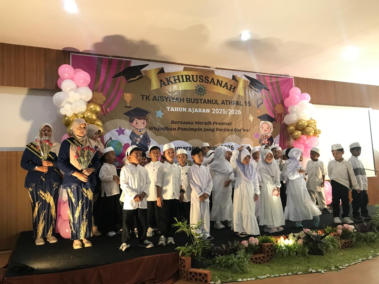 Barisan siswa laki-laki dan perempuan TK ABA 15 Semarang mengenakan pakaian serbaputih berdiri bersama guru-guru berbusana kebaya biru tua di atas panggung acara Akhirusannah berhias balon dan spanduk bertuliskan Tahun Ajaran 2025/2026.