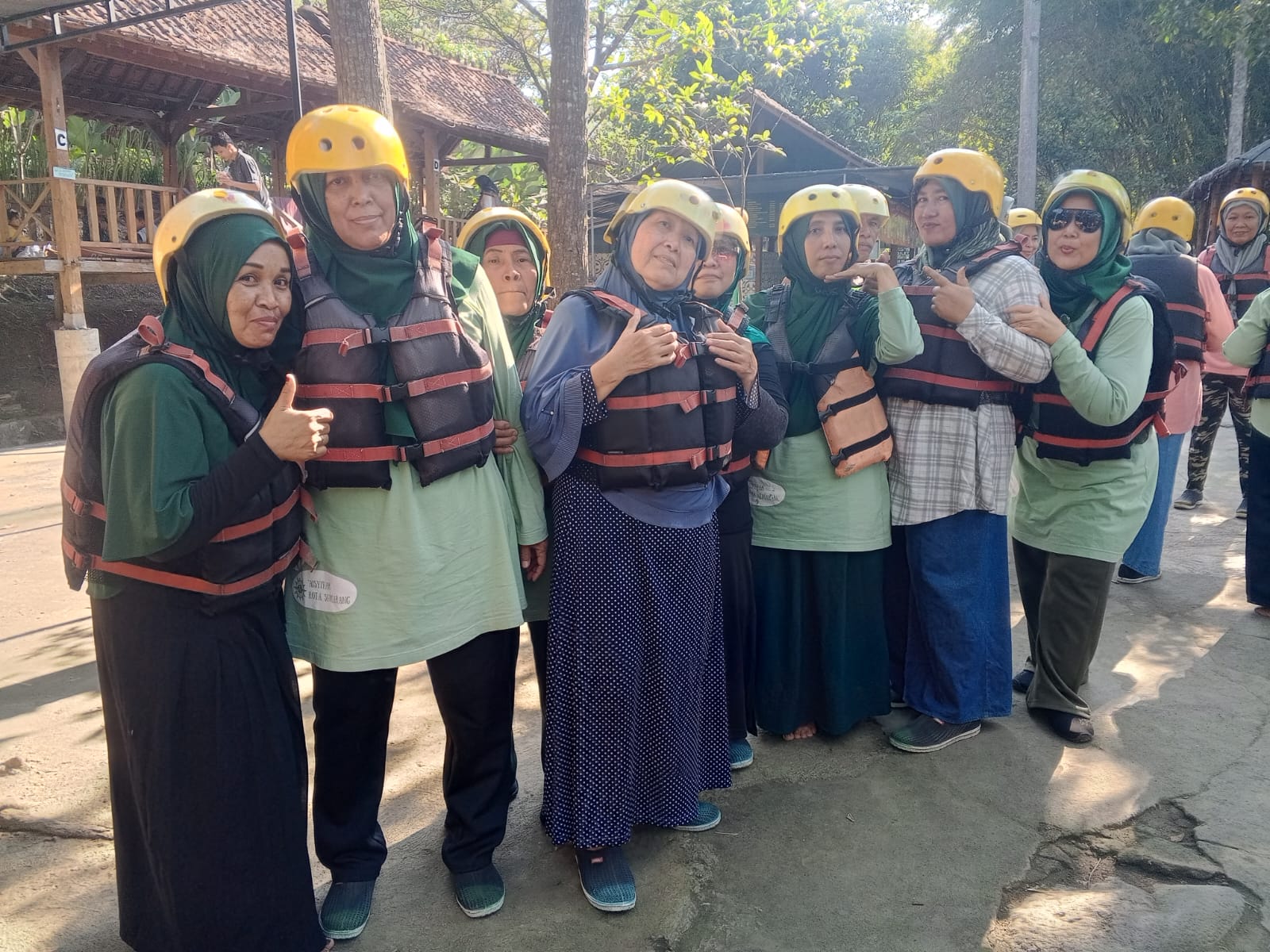 Sekelompok ibu-ibu jamaah Aisyiyah Bandarharjo Semarang tersenyum mengenakan helm pelindung kuning dan jaket pelampung hitam saat bersiap mengikuti outbound Islami di kawasan wisata alam Klaten.