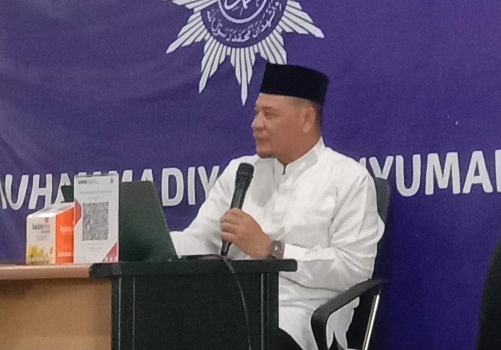 Dr. Fachrur Rozi, M.Ag. sedang duduk menyampaikan materi mengenai cara meraih takwa sejati di depan jamaah. Pria tersebut mengenakan baju koko putih dan peci hitam sembari memegang mikrofon, dengan latar belakang spanduk ungu berlogo Muhammadiyah Banyumanik.
