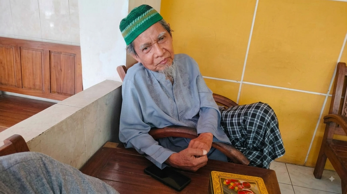 Potret almarhum Sa'di Zen Noor mengenakan peci hijau, baju koko abu-abu, dan sarung kotak-kotak sedang duduk santai dengan wajah teduh.