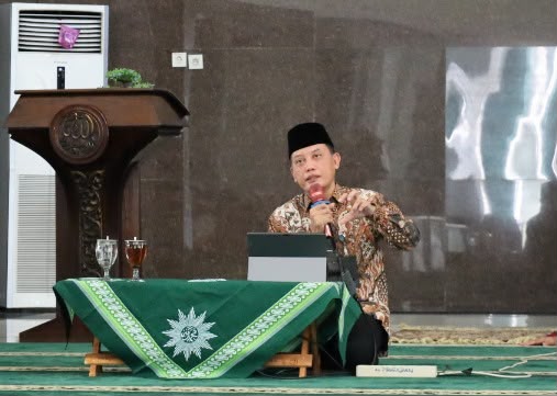 Wakil Rektor I Unimus Prof. Dr. Budi Santosa mengenakan batik dan peci hitam sedang memberikan tausiah tentang karakter Ulul Albab di depan meja berlogo Muhammadiyah.