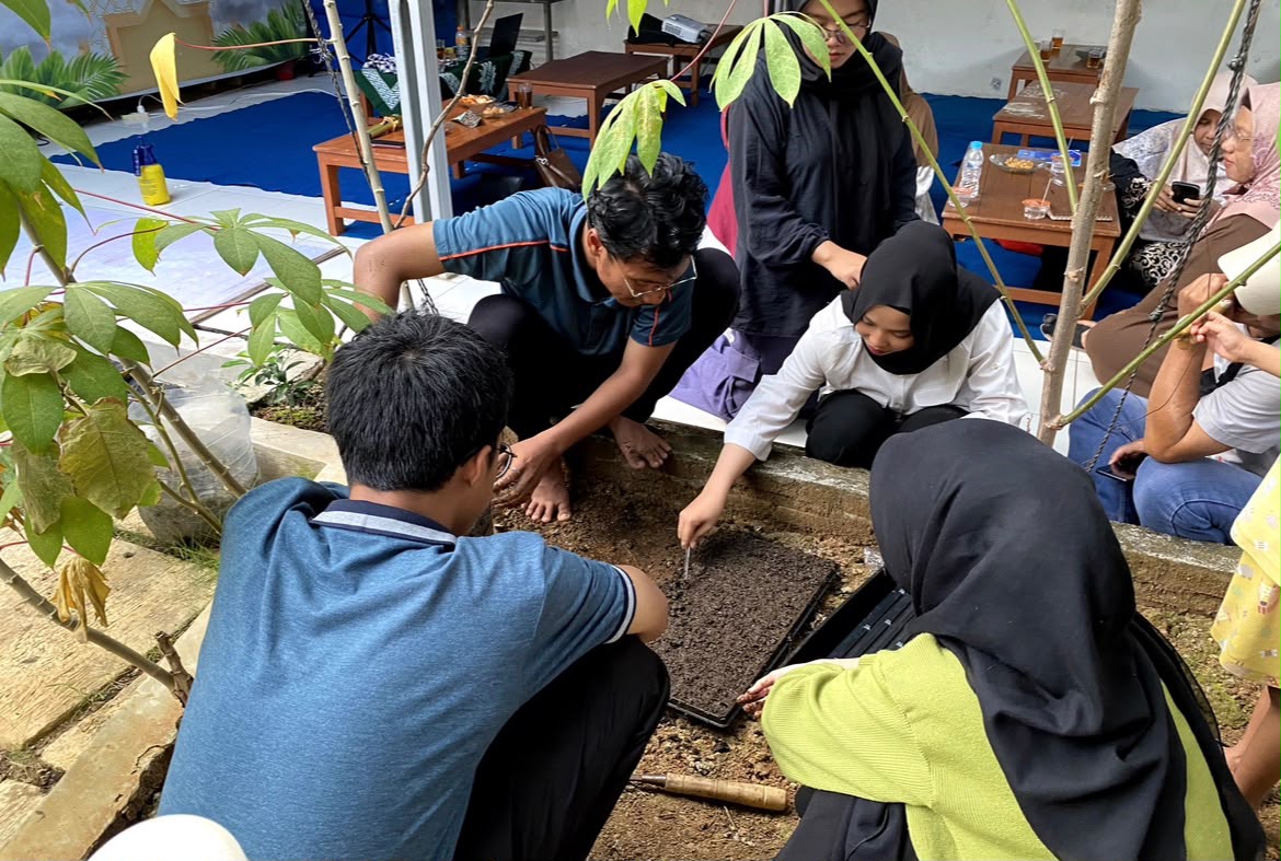 Sekelompok Angkatan Muda Muhammadiyah sedang belajar menanam bibit melon di bedengan taman komunitas selama lokakarya.