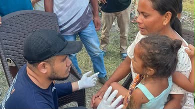 Relawan medis Muhammadiyah mengenakan sarung tangan putih sedang berbincang hangat dengan anak perempuan korban bencana di posko pengungsian sebagai bagian dari Bantuan Gempa NTT.