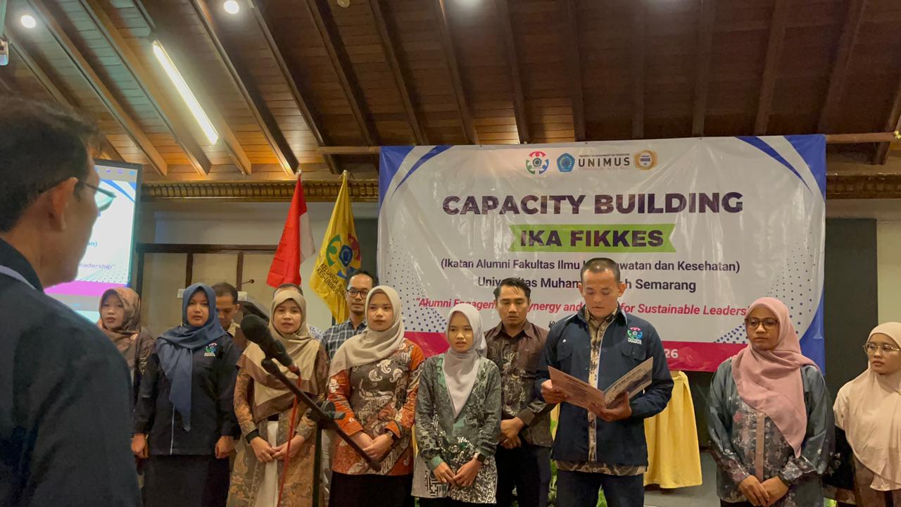 Suasana prosesi pengukuhan pengurus kompartemen IKA FIKKES Unimus berlatar spanduk Capacity Building di Salatiga sebagai wujud nyata kolaborasi tenaga kesehatan lintas profesi.