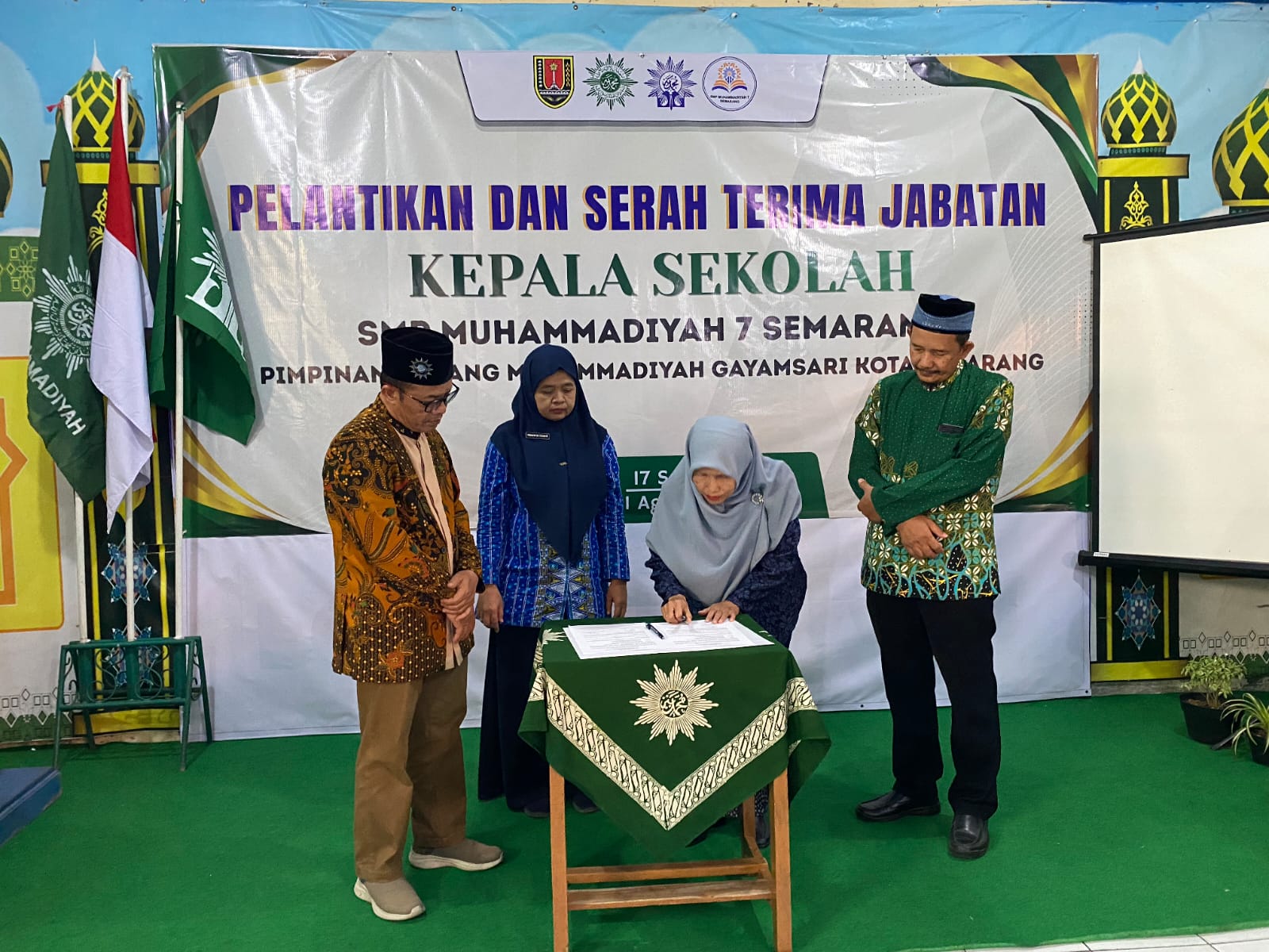Prosesi penandatanganan berkas sertijab Kepala SMP Muhammadiyah 7 Semarang oleh pejabat terkait yang disaksikan pengurus PDM dan PCM Gayamsari di depan spanduk acara.