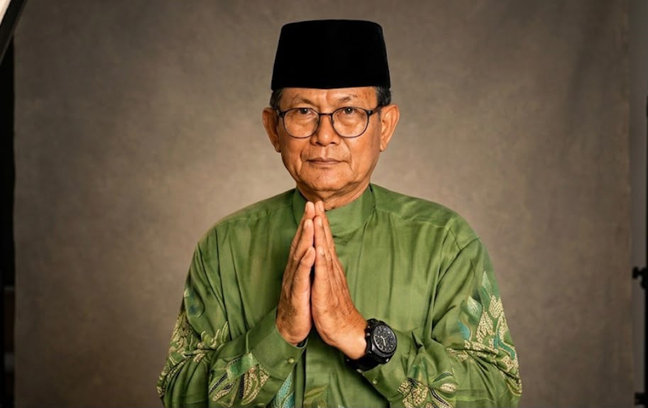 Potret Bapak Ahmad Suroto, Tokoh Muhammadiyah Semarang dari Mangkang, mengenakan peci hitam dan kemeja hijau dengan gestur tangan salam hormat.