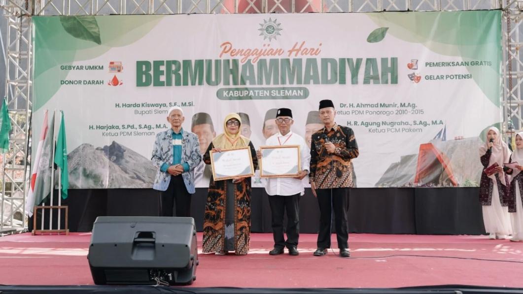 Penerima Wakaf Award memegang sertifikat penghargaan di atas panggung Pengajian Hari Ber-Muhammadiyah Kabupaten Sleman didampingi pimpinan daerah dan ketua panitia.