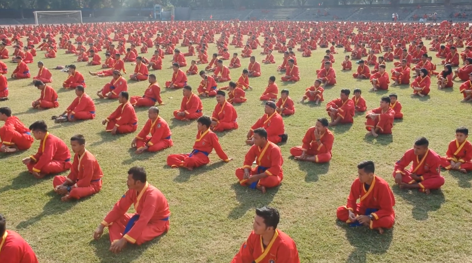 Ribuan pesilat Tapak Suci bereragam merah bersila rapi di tengah lapangan rumput hijau dalam persiapan atraksi kolosal Muktamar XVI Tapak Suci Semarang.