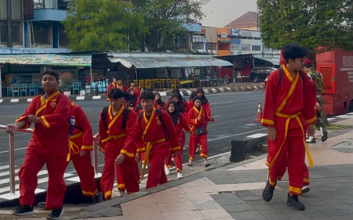 Rombongan pesilat remaja Tapak Suci berseragam merah-kuning berjalan rapi bersama di trotoar jalanan Kota Semarang dengan ceria.