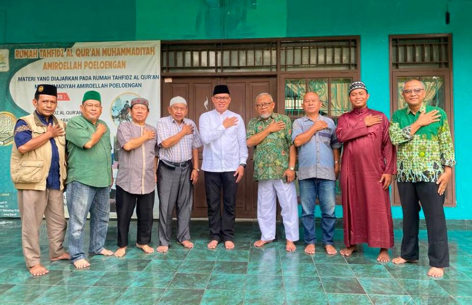 Sembilan jajaran pengurus MPKS PP Muhammadiyah dan tokoh lokal berfoto bersama di depan bangunan bercat hijau dengan gestur tangan kanan di dada kiri.