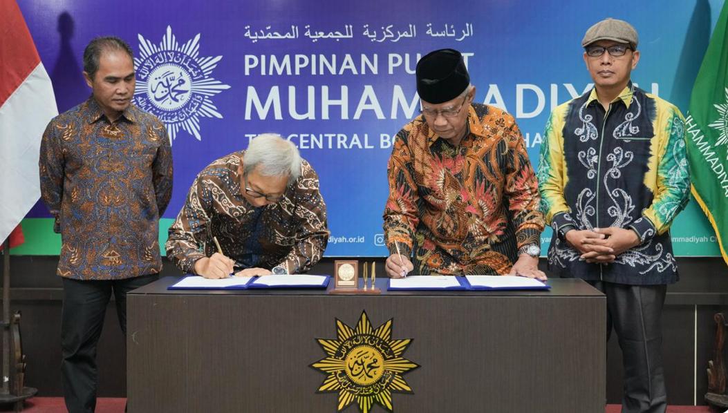 Ketua Umum PP Muhammadiyah Haedar Nashir dan Direktur Indosat Muhammad Buldansyah menandatangani berkas MoU di meja dengan logo Muhammadiyah, didampingi dua pejabat lembaga di latar belakang biru bertuliskan Pimpinan Pusat Muhammadiyah.