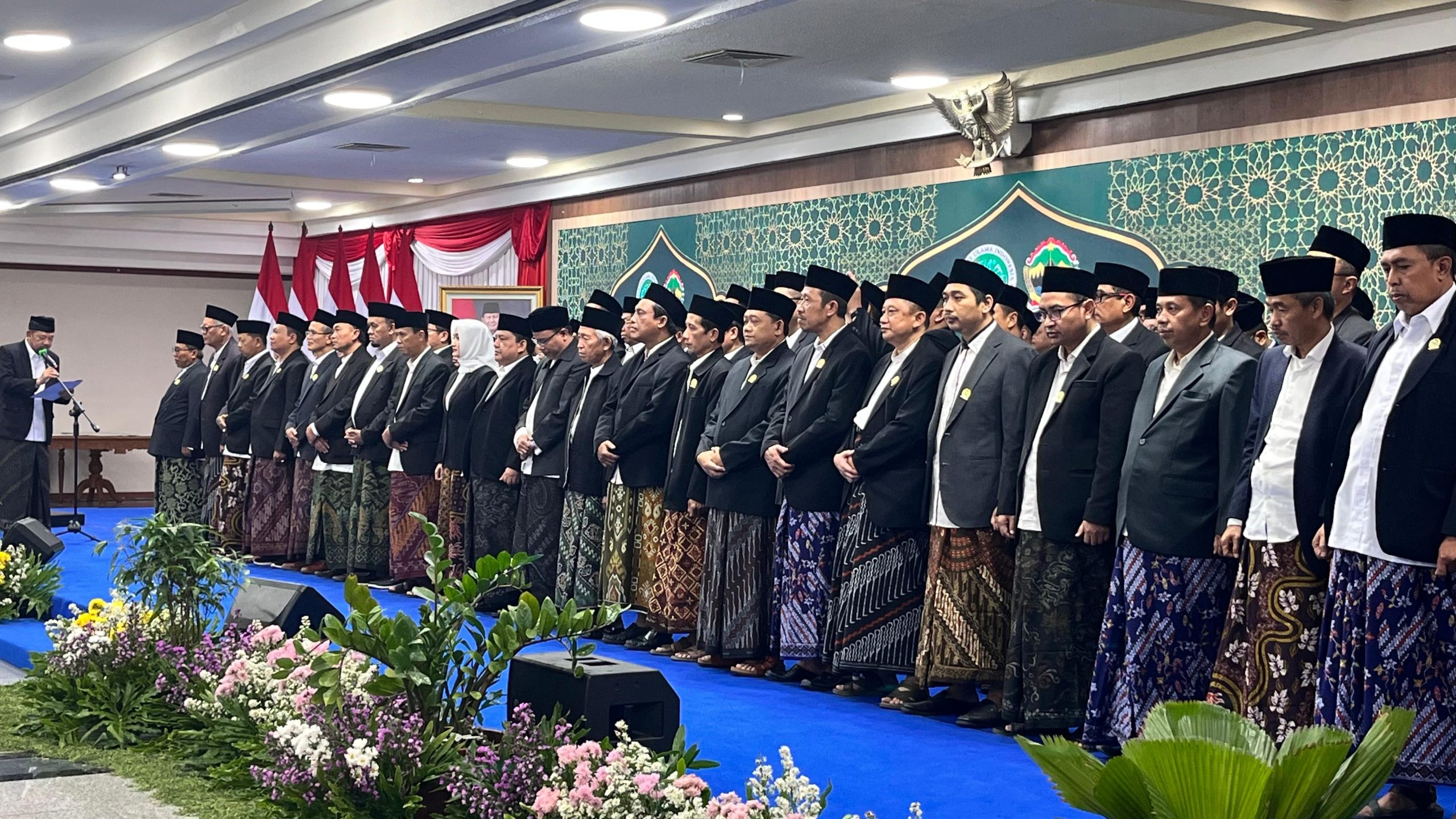 Puluhan pengurus MUI Jawa Tengah mengenakan jas hitam, peci hitam, dan sarung batik berdiri rapi di atas panggung dalam prosesi pengukuhan di Gedung Gradhika Bhakti Praja.
