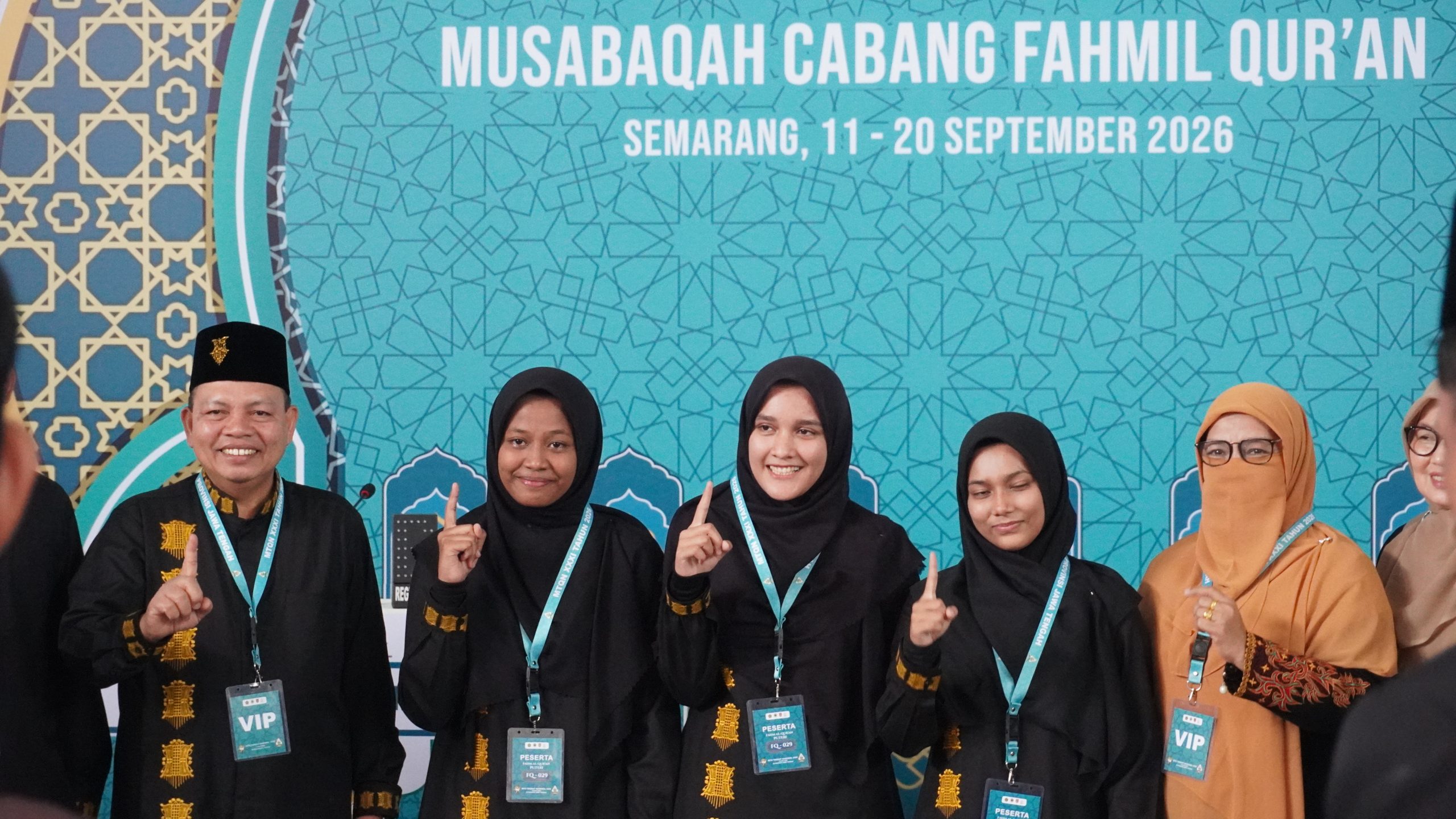 Tiga peserta putri Kafilah Aceh Fahmil Quran, Azka, Kayyisa, dan Izza, berpose gembira dengan isyarat satu jari bersama pendamping di panggung MTQ Nasional 2026 Semarang setelah meraih juara dengan skor tertinggi 1505.
