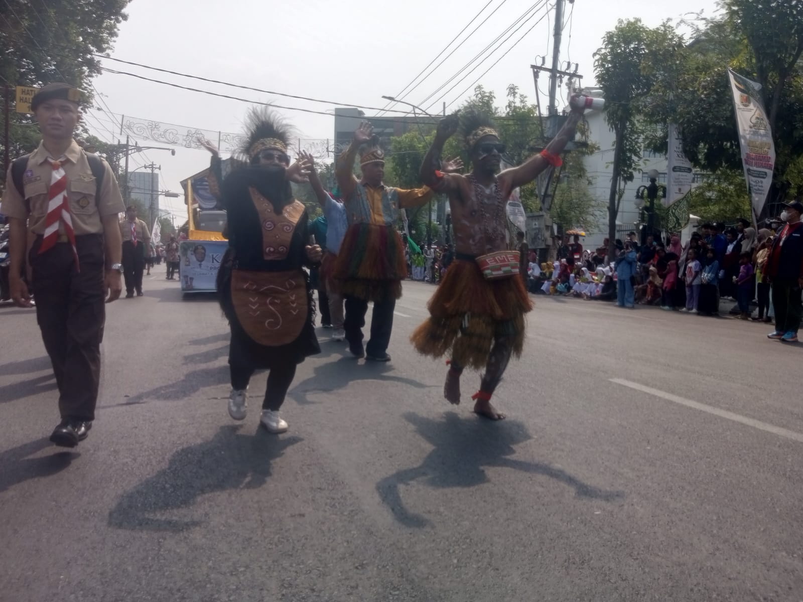 Peserta kafilah Papua Barat mengenakan pakaian adat tradisional dan menari dengan penuh semangat dalam pawai ta'aruf MTQ Nasional ke-31 di Semarang, disaksikan oleh warga di pinggir jalan raya.