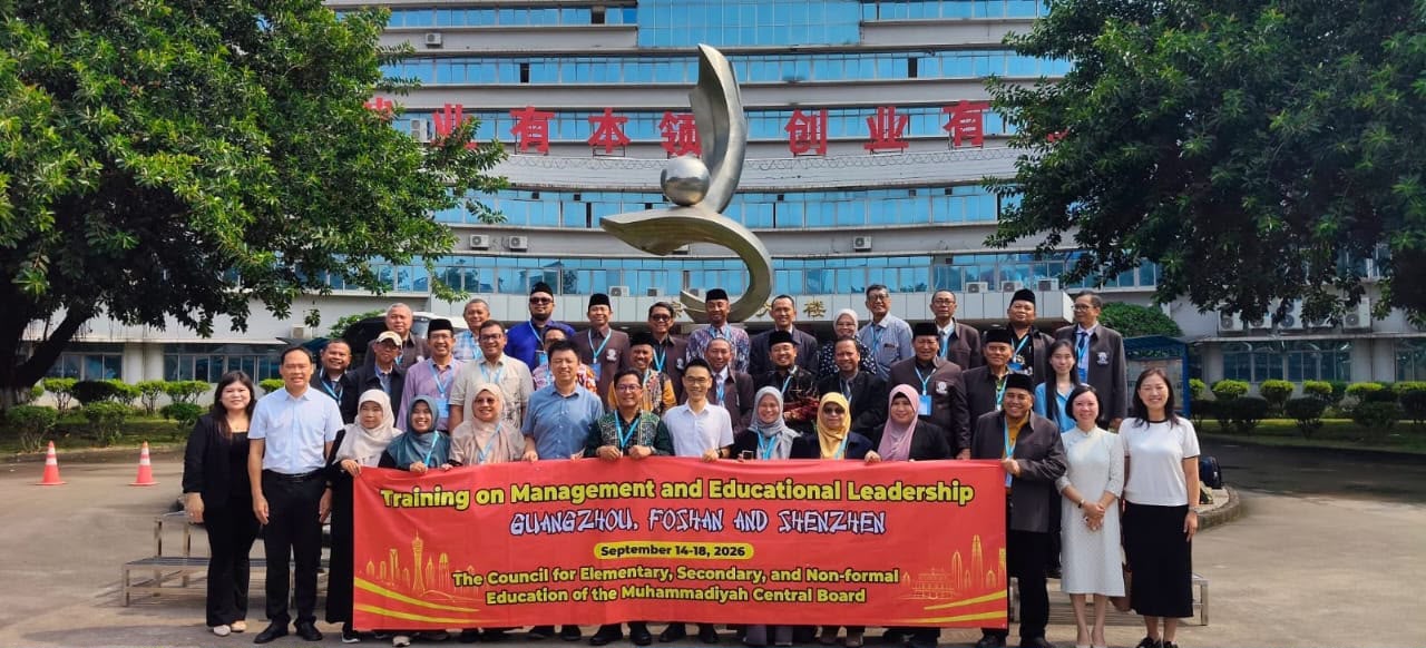 Rombongan 32 pimpinan dan kepala sekolah Muhammadiyah membentangkan spanduk pelatihan bersama mitra lokal di depan gedung berarsitektur modern China.