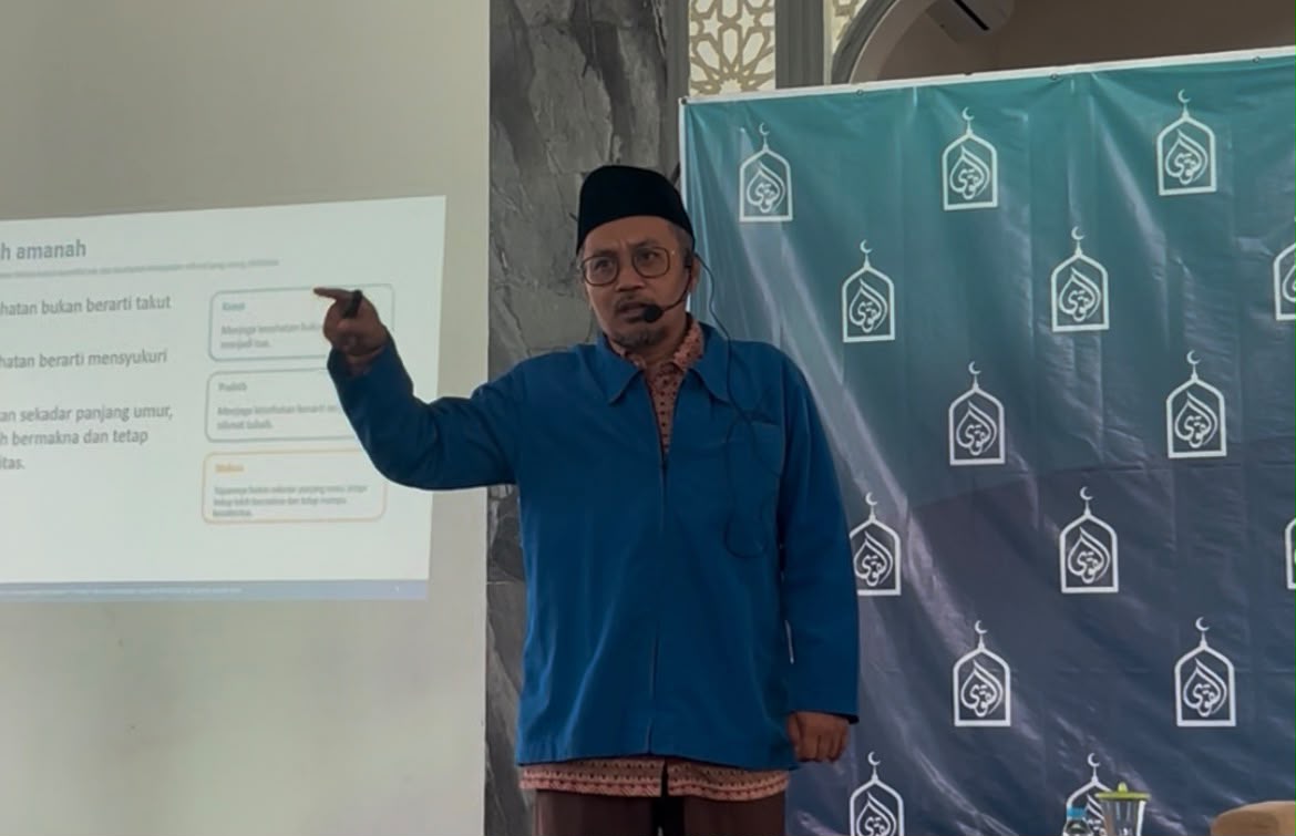 Ustadz Zainal Abidin, S.S.T.Ft.R., M.H., sedang memberikan ceramah kesehatan di Masjid At-Taqwa, menunjuk slide proyektor bertema Kesehatan Adalah Amanah.