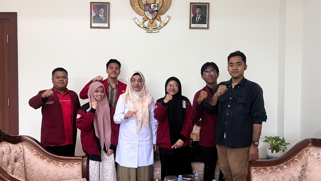 Pengurus IMM UIN Walisongo Komisariat Paripatetik berjas merah maroon mengepalkan tangan berfoto bersama Wakil Rektor III Dr. Hj. Umul Baroroh, M.Ag. di ruang kerja.