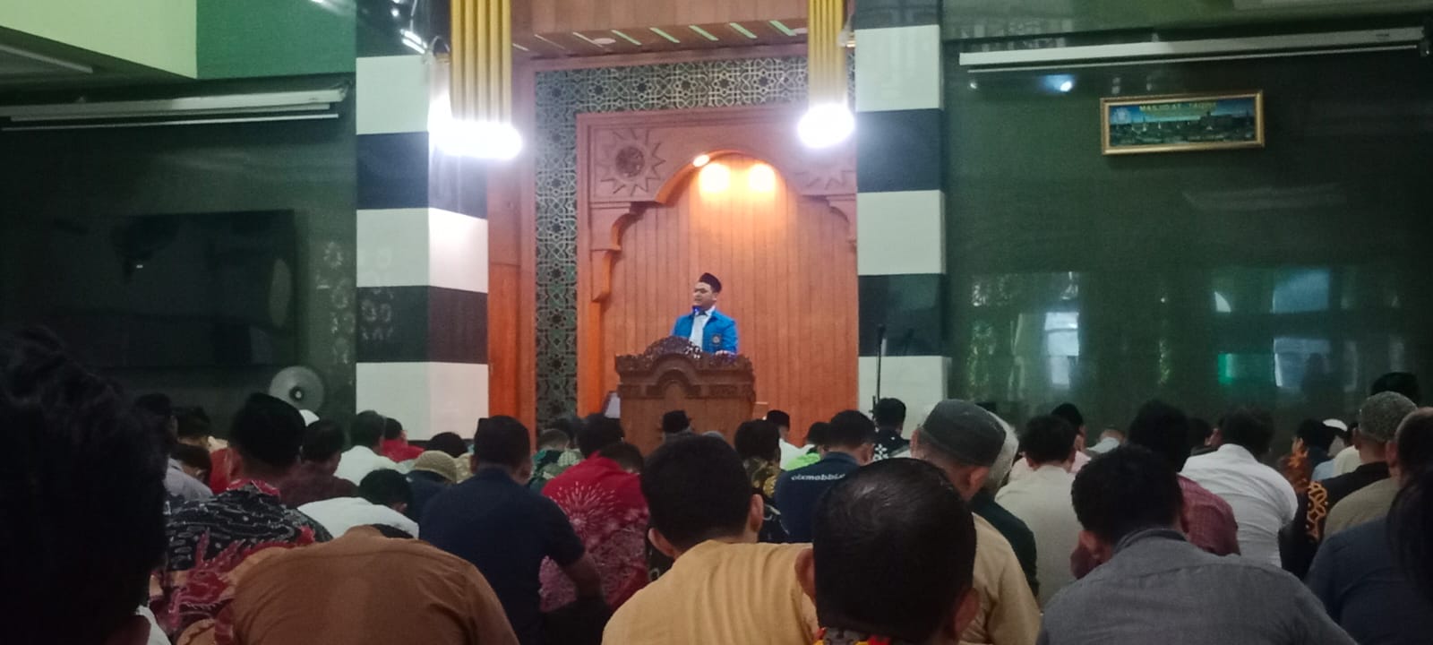 Khatib Ustaz Amiril Edi Pranomo berjas biru Pemuda Muhammadiyah berdiri di mimbar kayu Masjid At-Taqwa PDM Kota Semarang di hadapan ratusan jemaah yang duduk menyimak dari arah belakang.