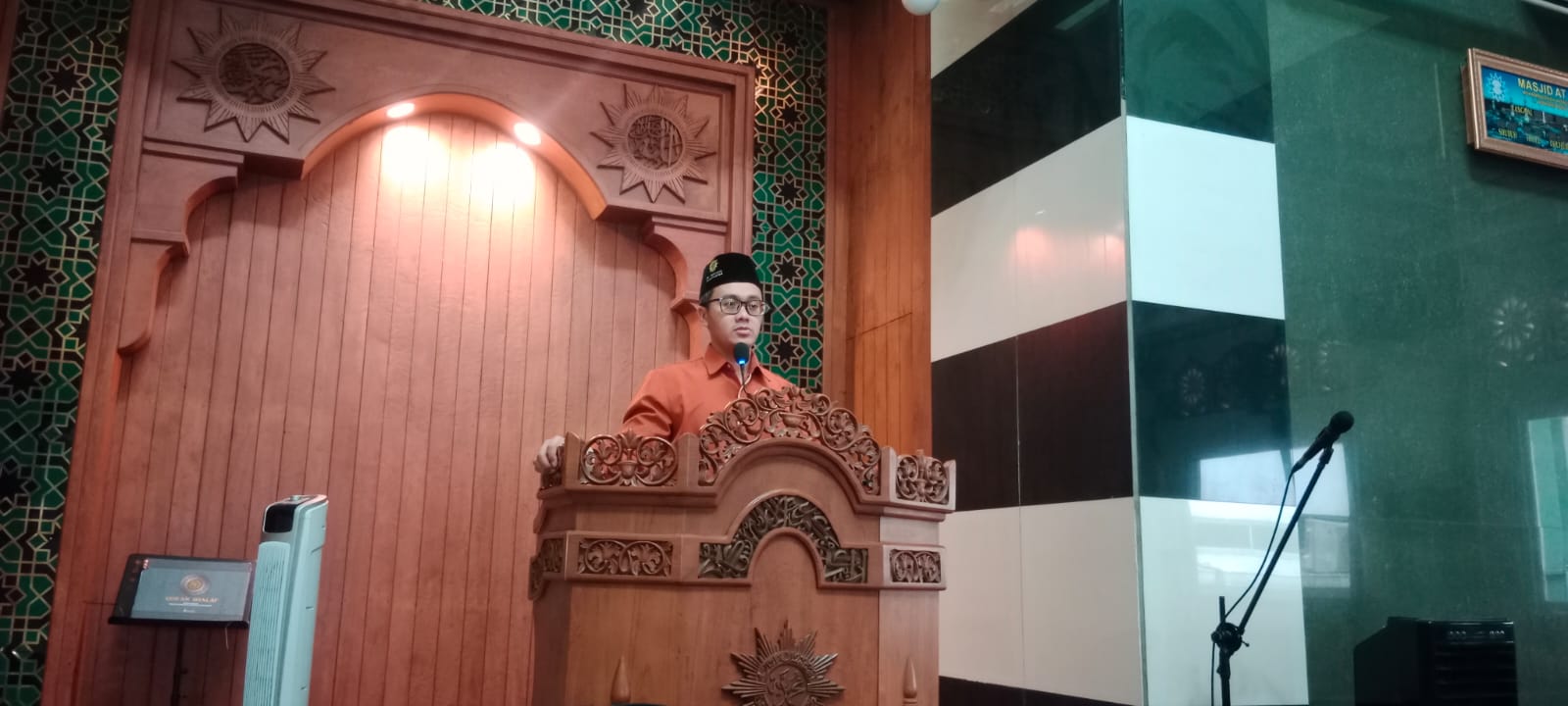 Penceramah Ustadz Ra'ad Noor Fattah berkemeja oranye dan peci hitam berdiri di mimbar kayu Masjid At-Taqwa PDM Kota Semarang memberikan tausiah di depan mihrab masjid.
